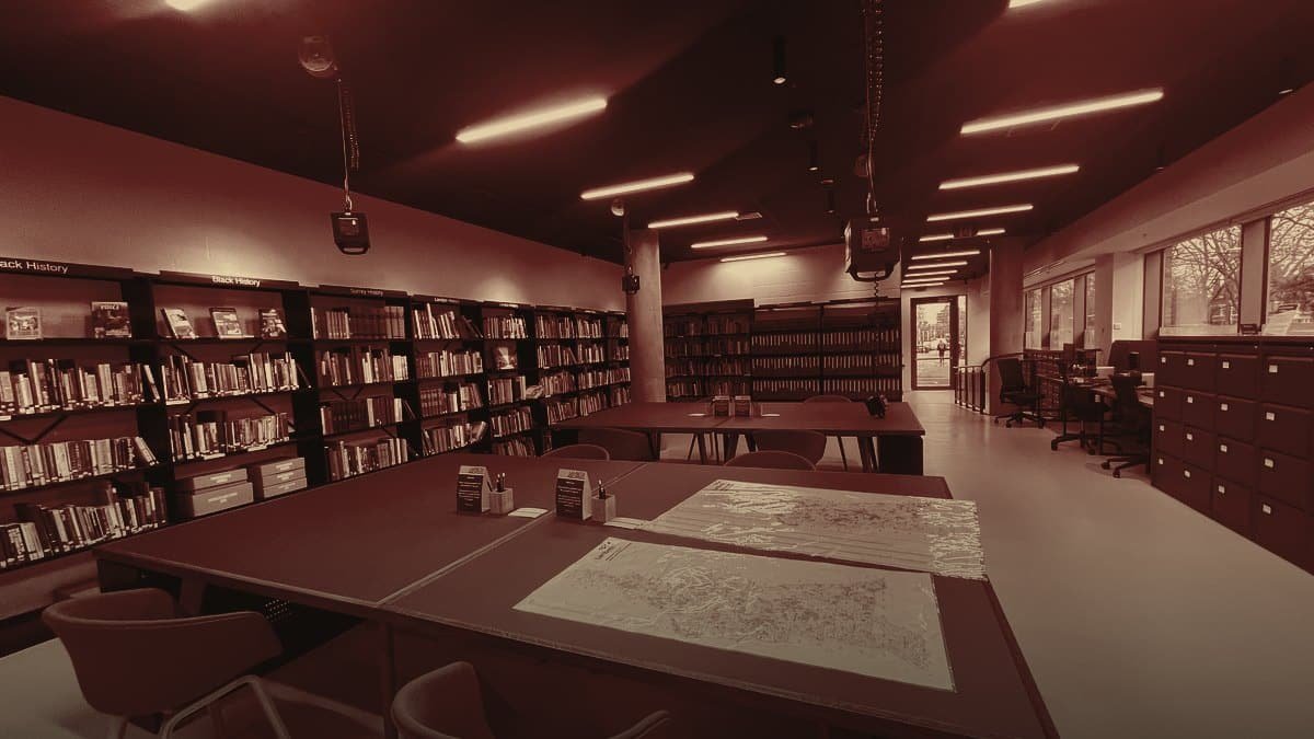 Sala di studio di un archivio: tavoli con mappe aperte, scaffali di volumi, nessuna persona